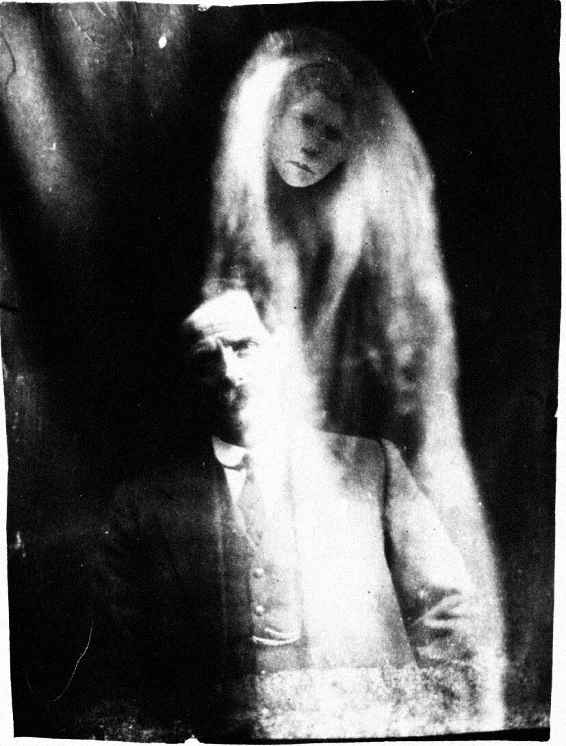 Early 20th century spirit photograph: a ghostly woman with long hair hovering over a seated man. Click to go back.